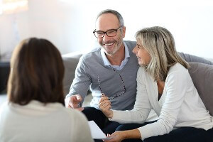 Happy older couple on couch speaking with professional